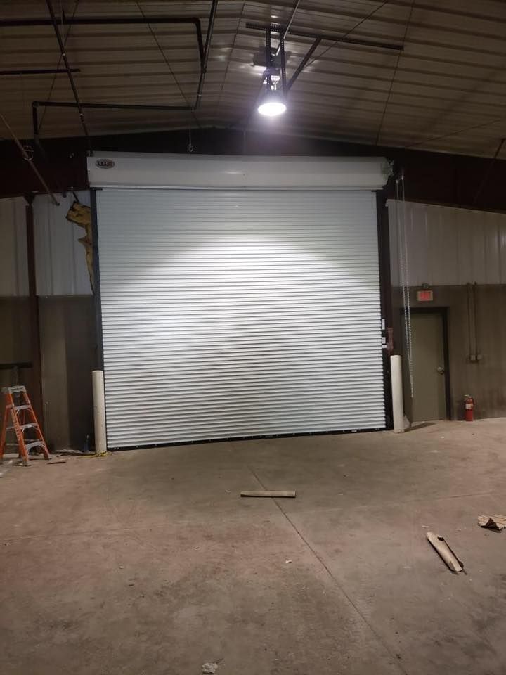 Large, closed, white roll-up garage door in an industrial warehouse.