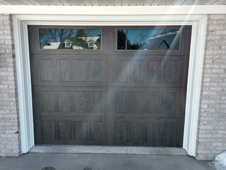 Brown garage door with two window panels above, set in a white-trimmed opening.