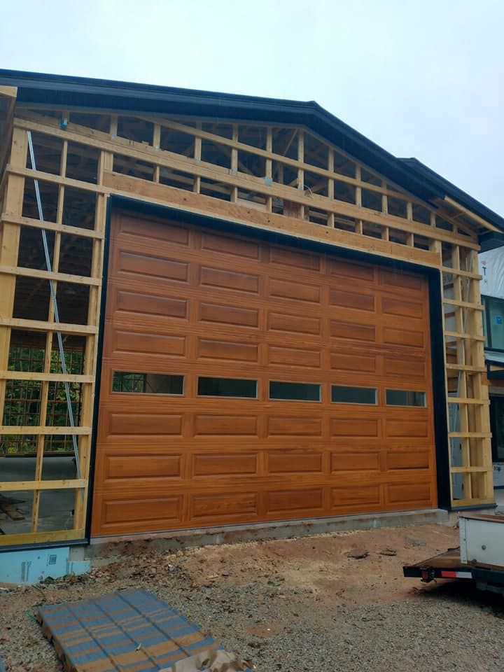 Brown garage door installed in a wooden frame during construction, with rectangular glass windows.