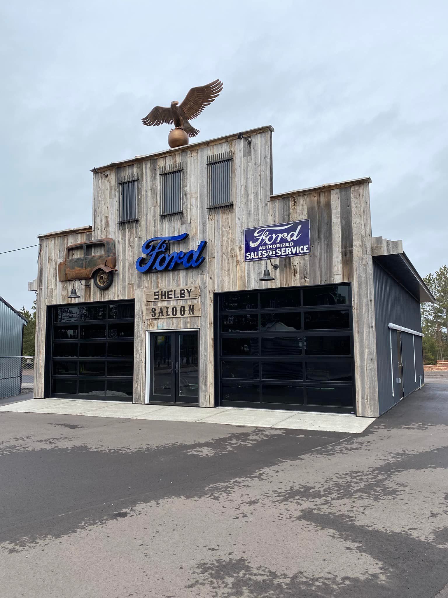 Rustic building with Ford sign and eagle sculpture on roof.