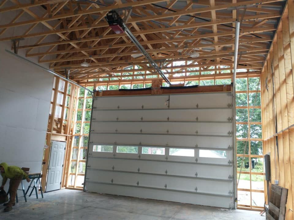 Garage door installation in progress; wood framing, partially installed door, open ceiling.