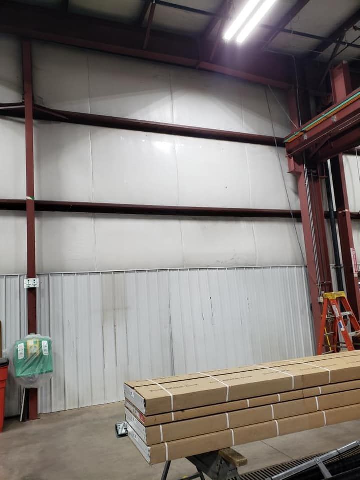 Warehouse interior with metal beams, white paneling, and stacked cardboard boxes.