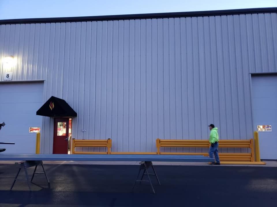 Exterior view of a building with a yellow barrier and a person walking towards a red door.