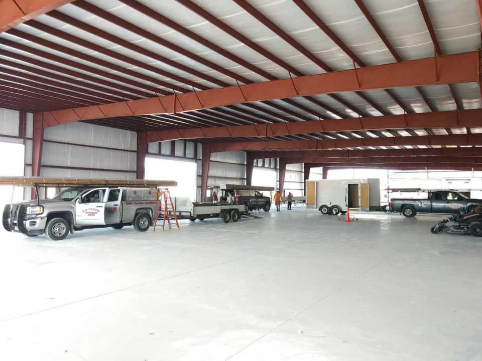 Metal building interior with trucks, trailers, and construction materials.