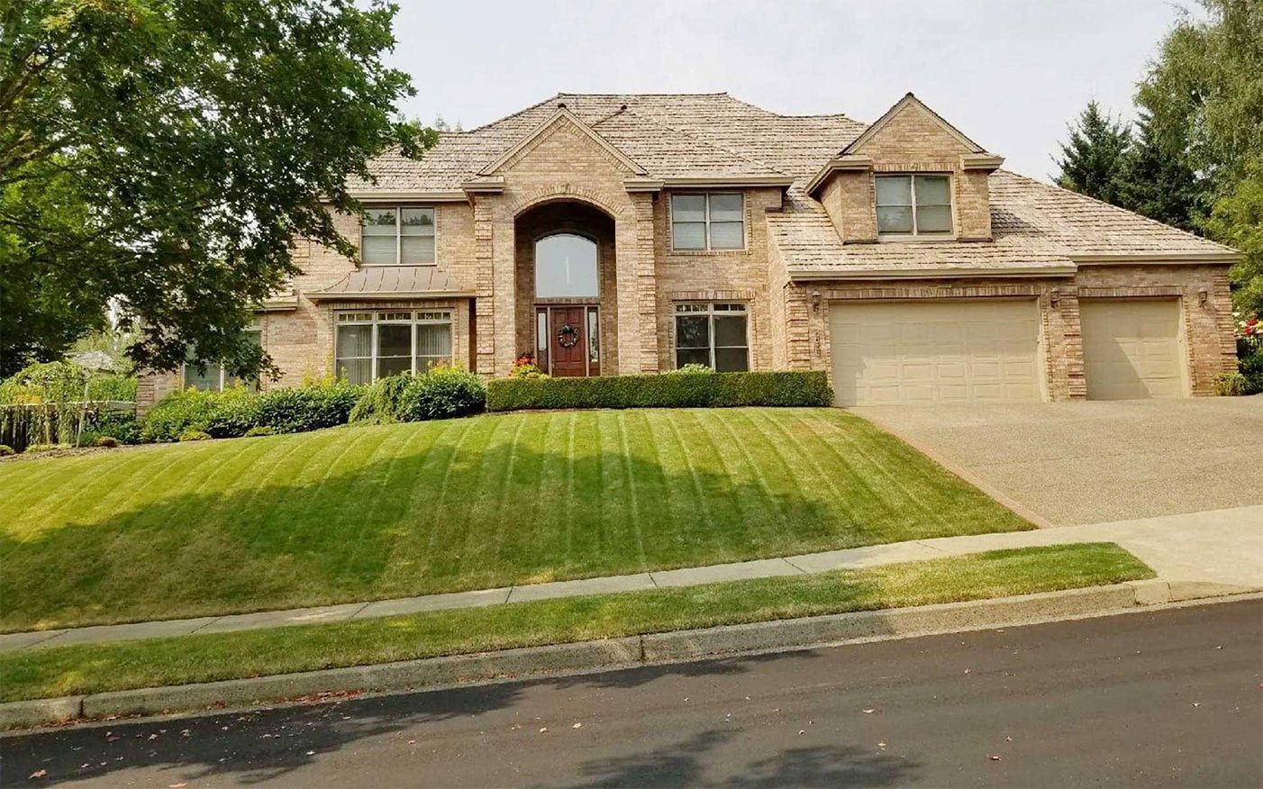 A large brick house with a lush green lawn in front of it