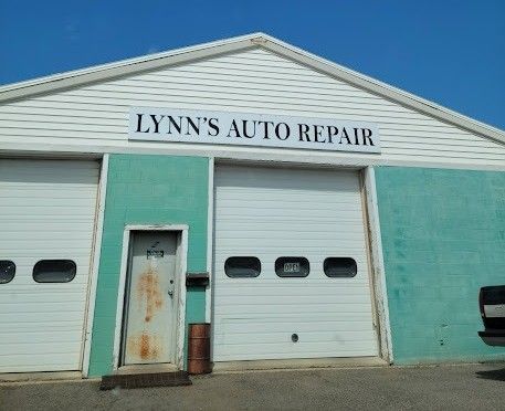 Lynn's Auto Repair shop with white garage doors and a sign above. Teal walls.
