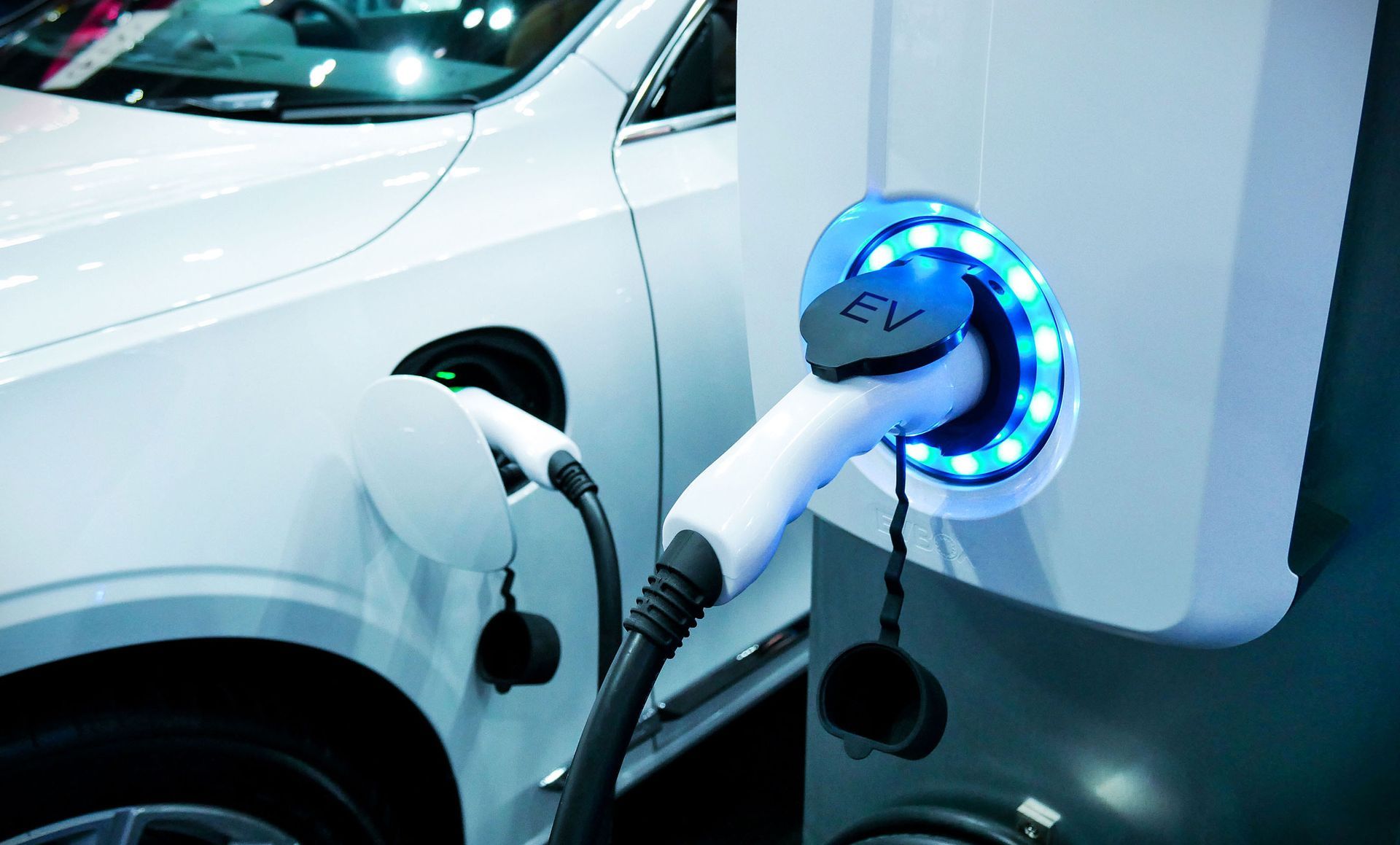 A white electric car is being charged at a charging station.