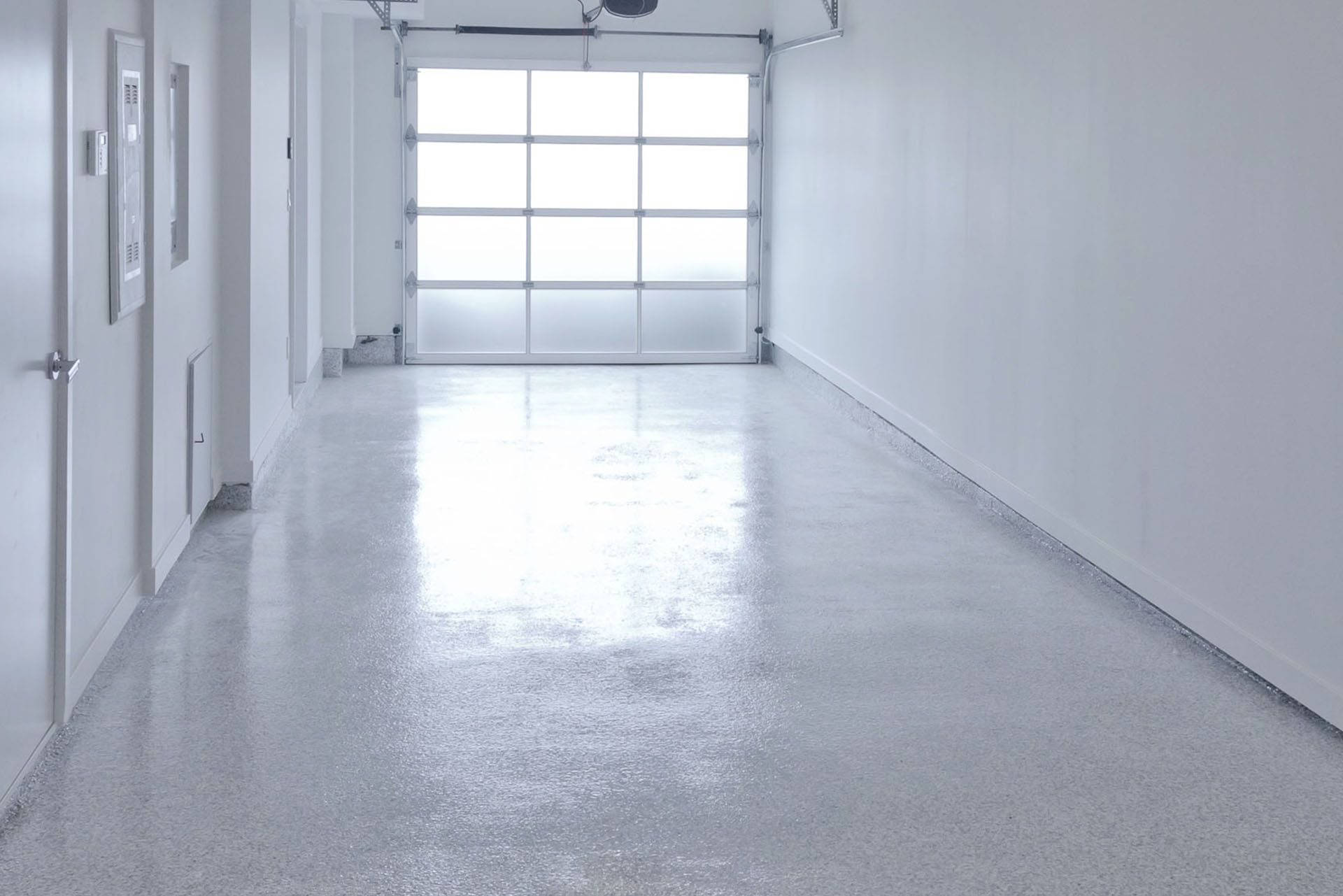 Empty white hallway with a glossy floor and closed garage-style door at the end