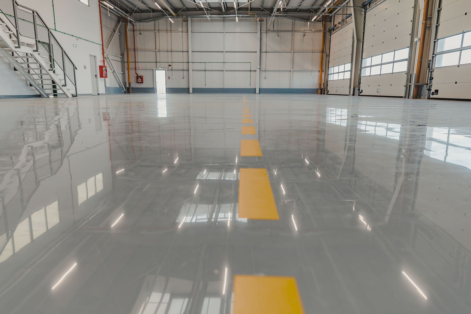 Empty hangar with a glossy gray floor and a yellow centerline stretching into the distance