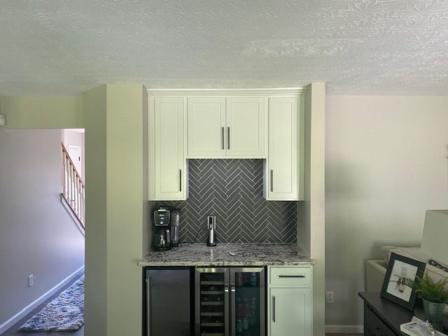 A kitchen with white cabinets and a wine cooler.