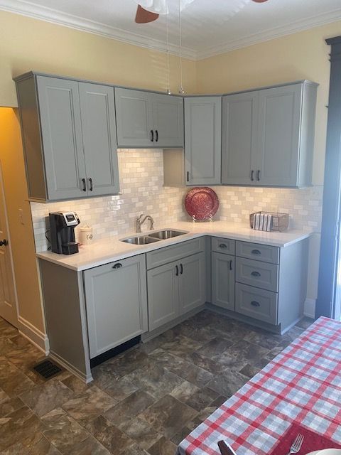 A kitchen with gray cabinets and a red and white checkered table cloth.