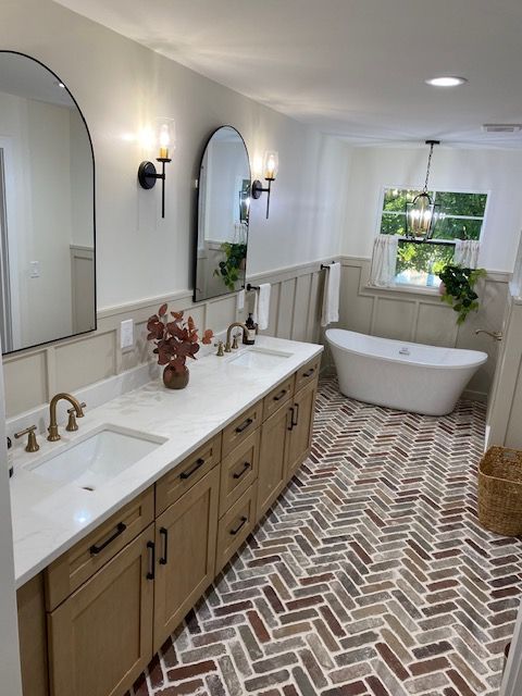 A bathroom with two sinks , two mirrors and a bathtub.