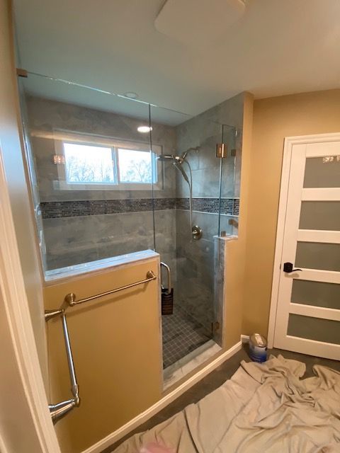 A bathroom with a walk in shower and a window.