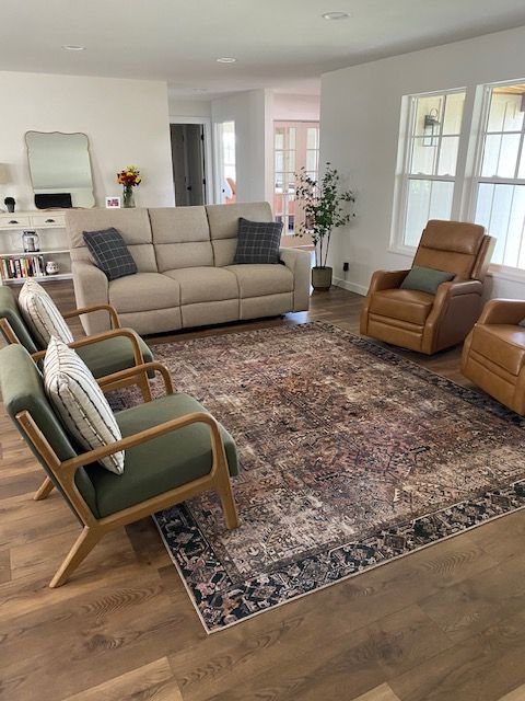 A living room with a couch , chairs , and a rug.