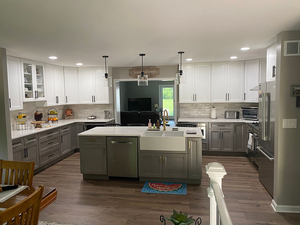 A kitchen with cabinets, white counter tops , stainless steel appliances and a large island