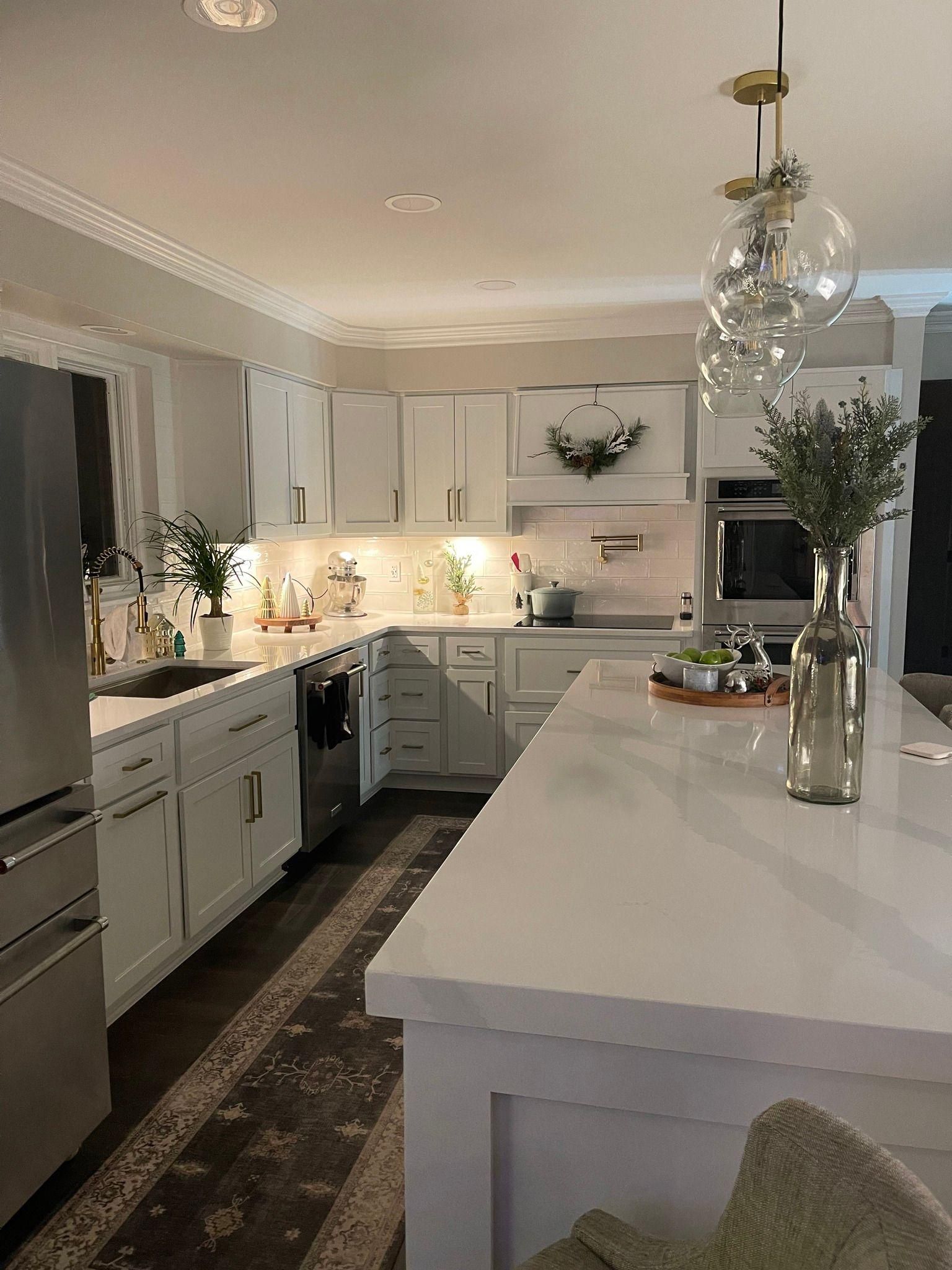 A kitchen with white cabinets, stainless steel appliances, and a large island.