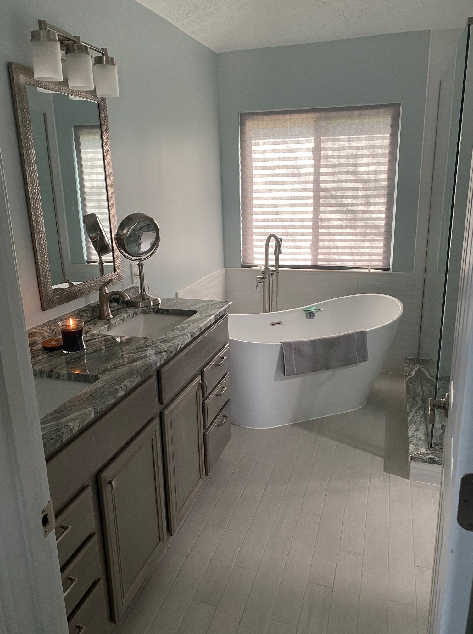 A bathroom with a tub, sink, mirror and window
