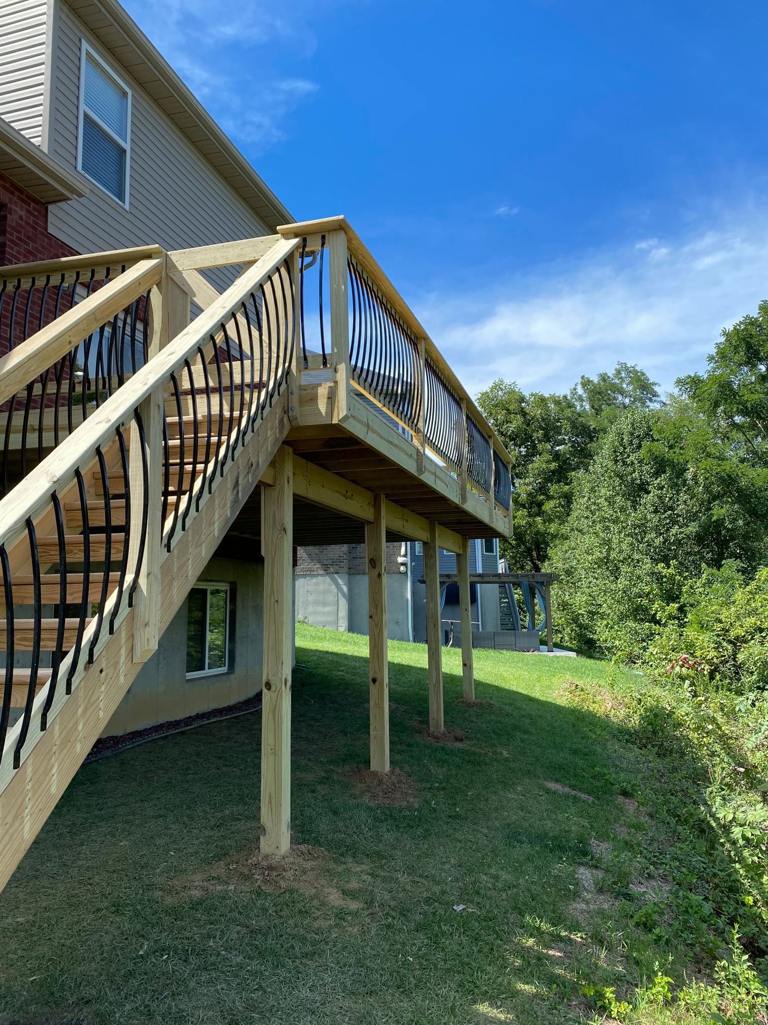 A wooden deck with stairs leading up to it is in front of a house.