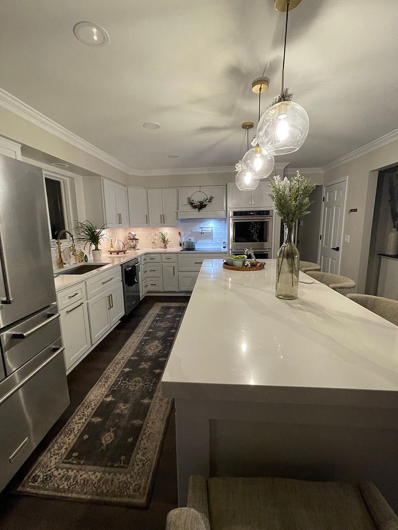 A kitchen with white cabinets, stainless steel appliances, a large island and a rug