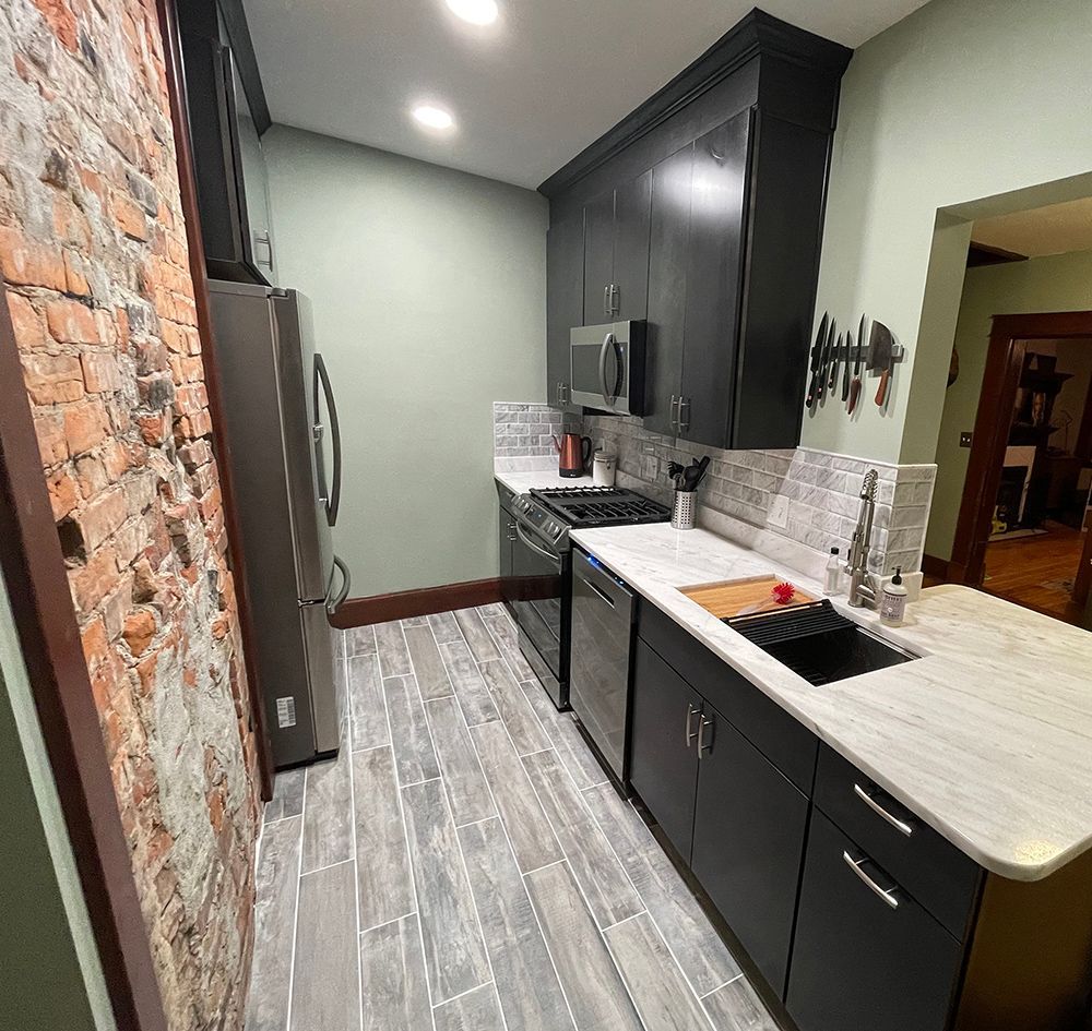 A kitchen with black cabinets and a brick wall