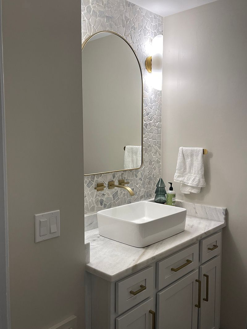 A bathroom with a sink, mirror and cabinets