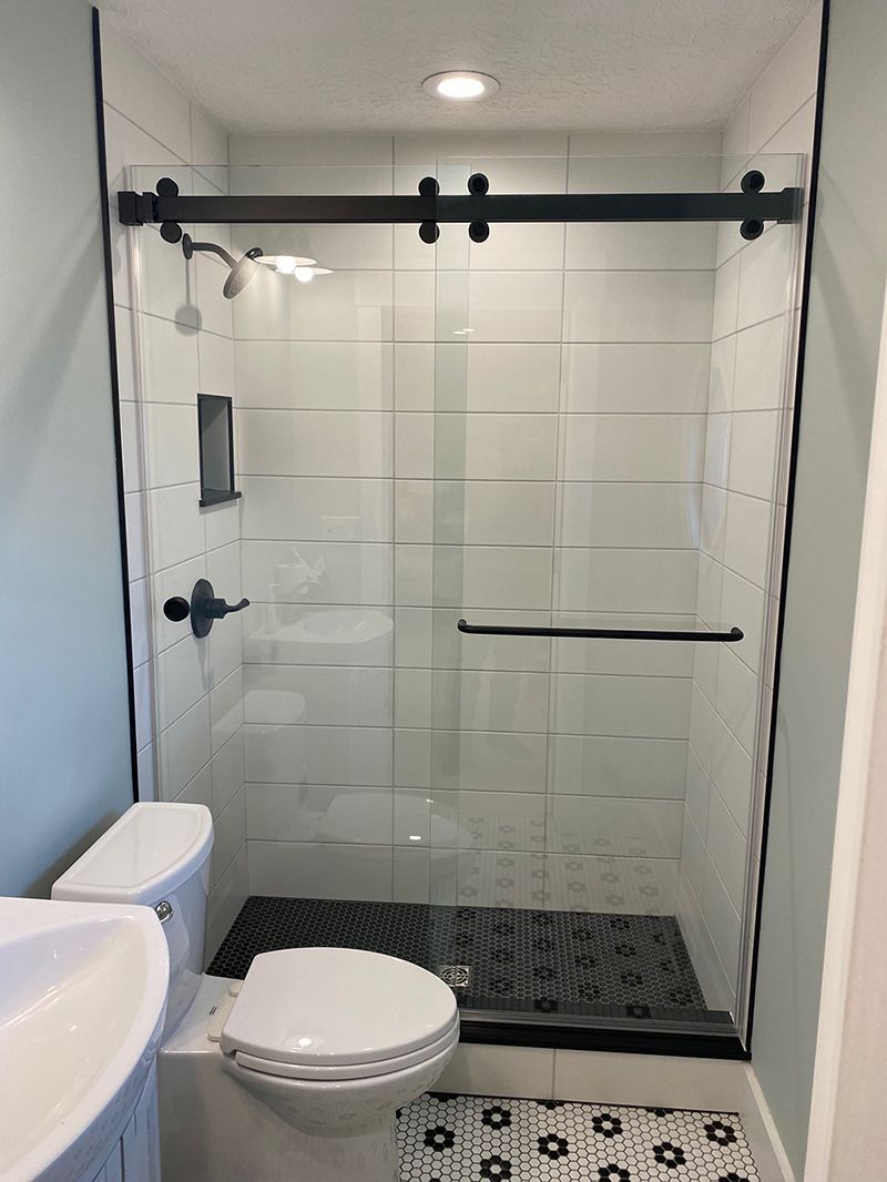 A bathroom with a toilet, sink, shower and sliding glass door