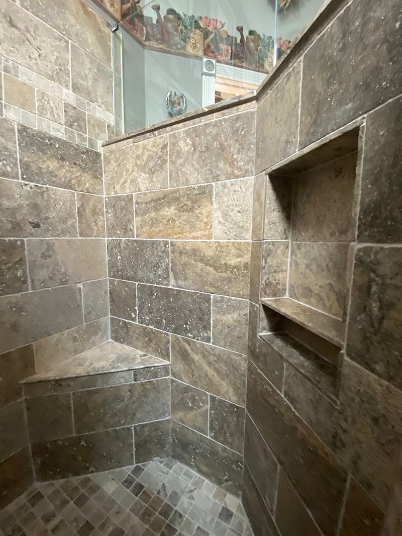 A shower with a corner bench and a shelf in it