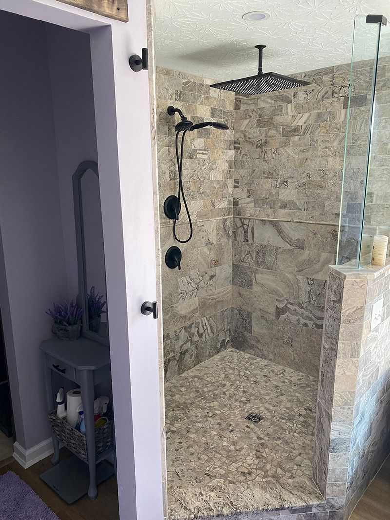 A bathroom with a walk in shower and a purple rug