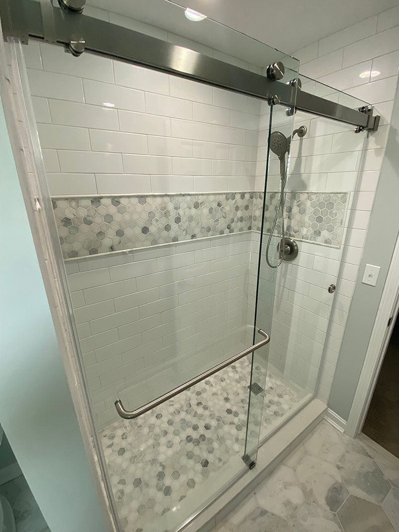 A bathroom with a sliding glass shower door and a shower head