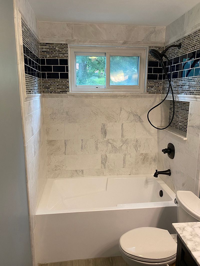 A bathroom with a tub, toilet and shower