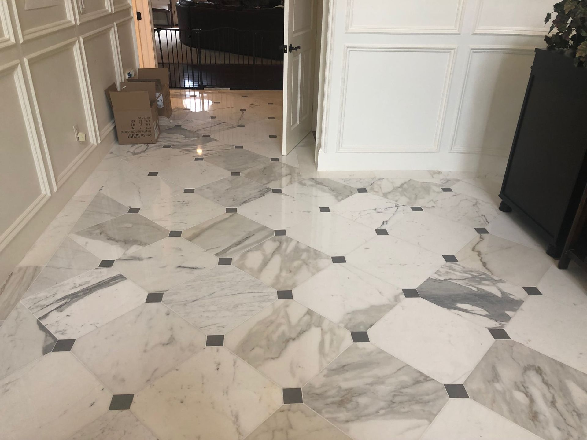 A white marble floor with black squares in a hallway.