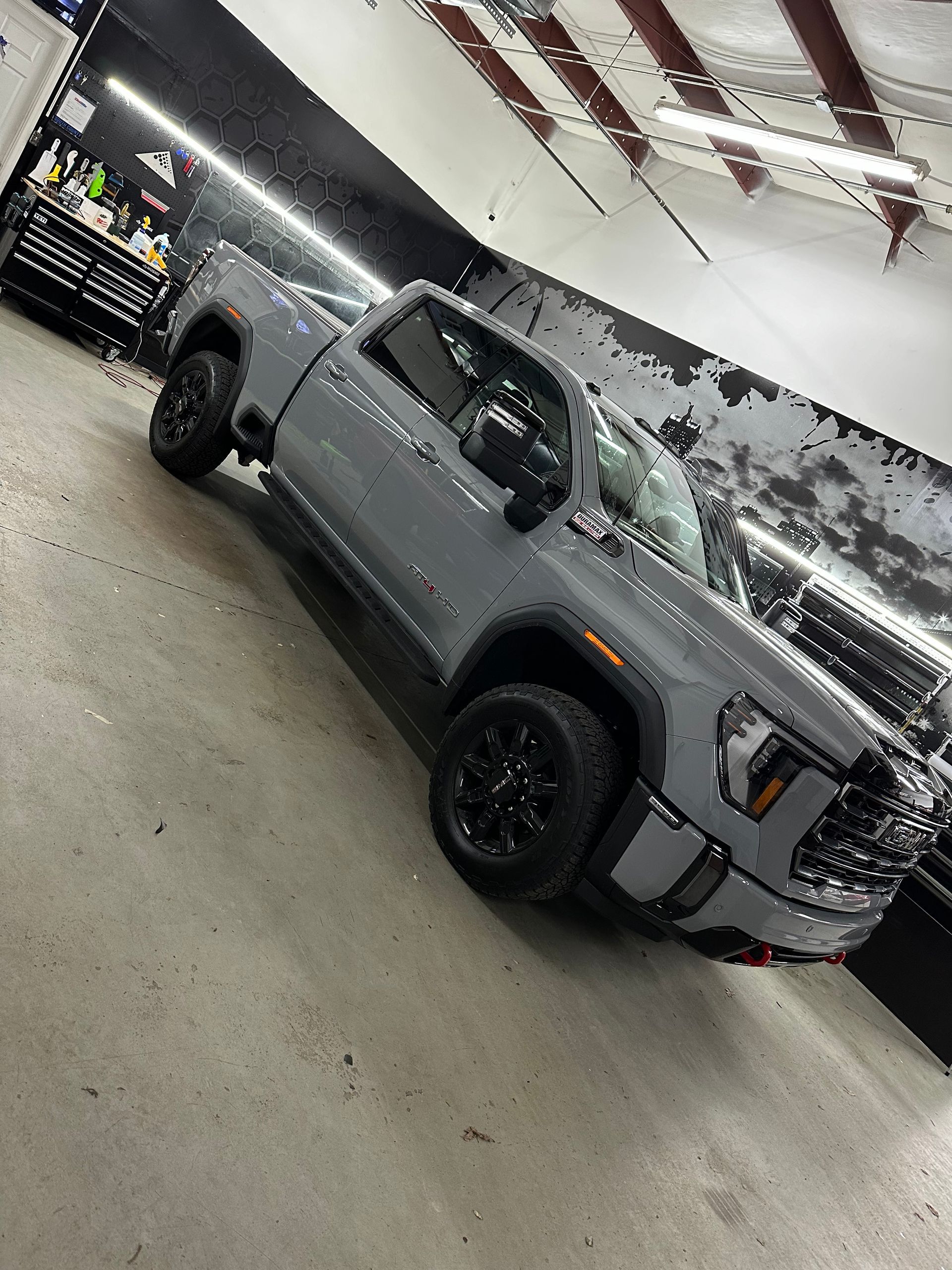 Gray GMC truck in a garage. Black wheels, angled shot.