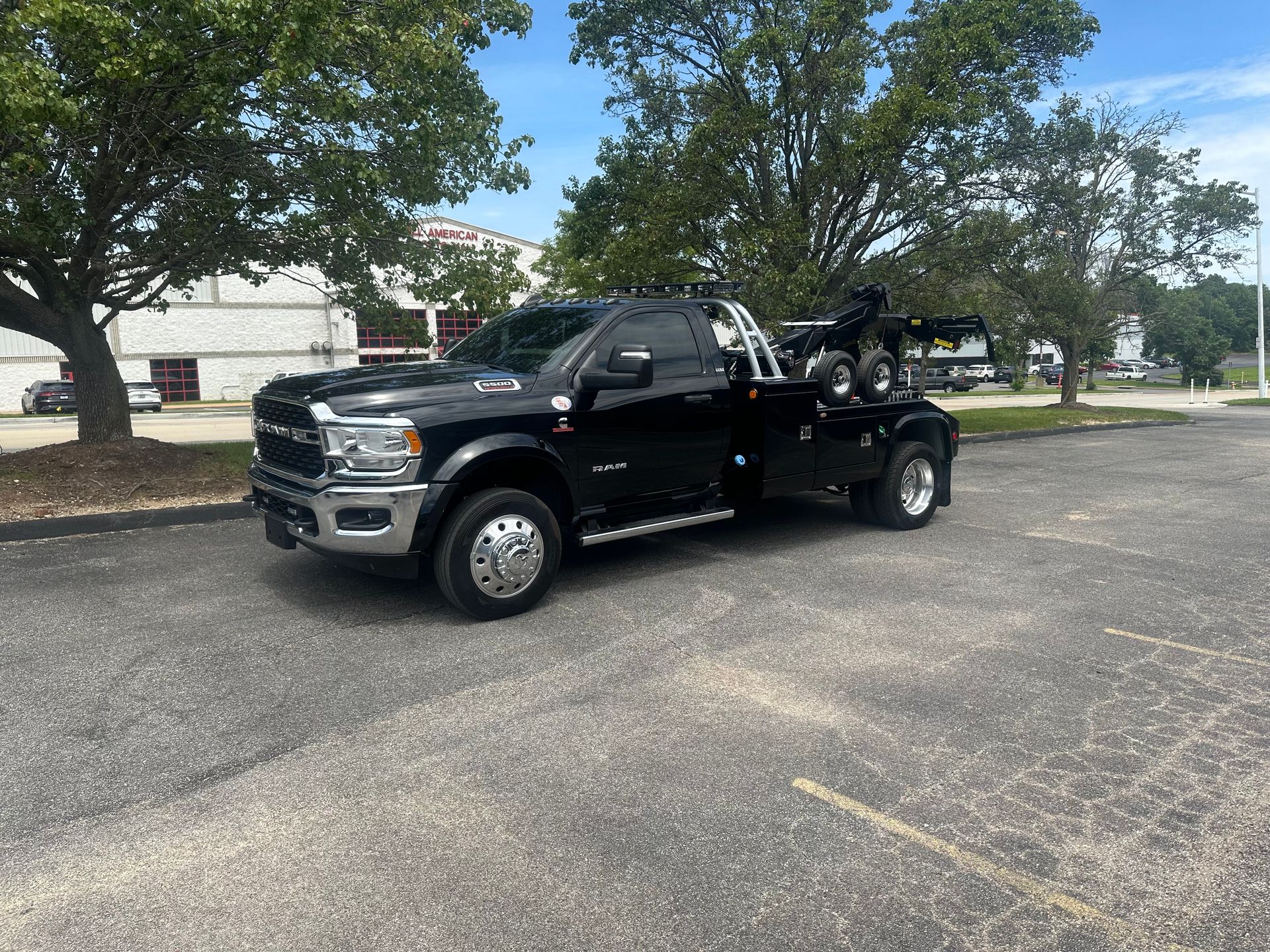 Black tow truck parked on asphalt; trees in background.