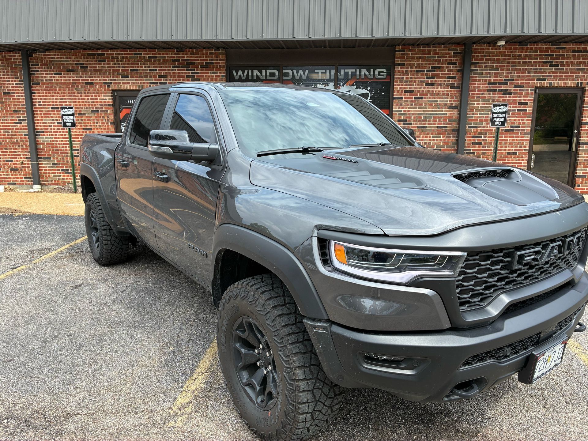 Gray Ram TRX truck parked in front of a window tinting business.