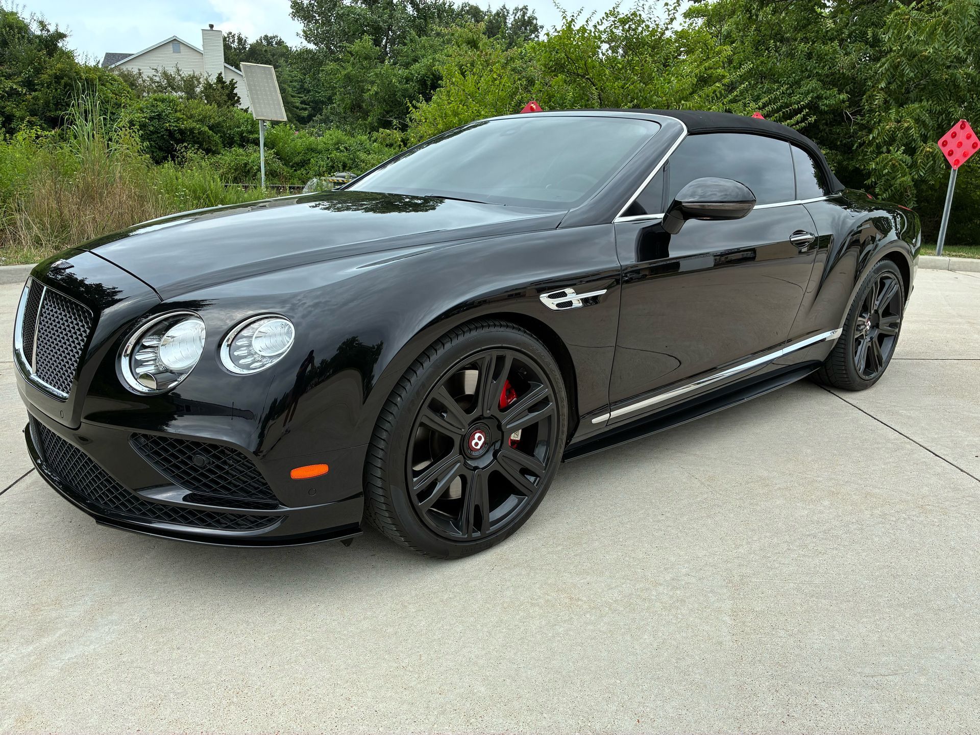 Black Bentley convertible parked on asphalt.