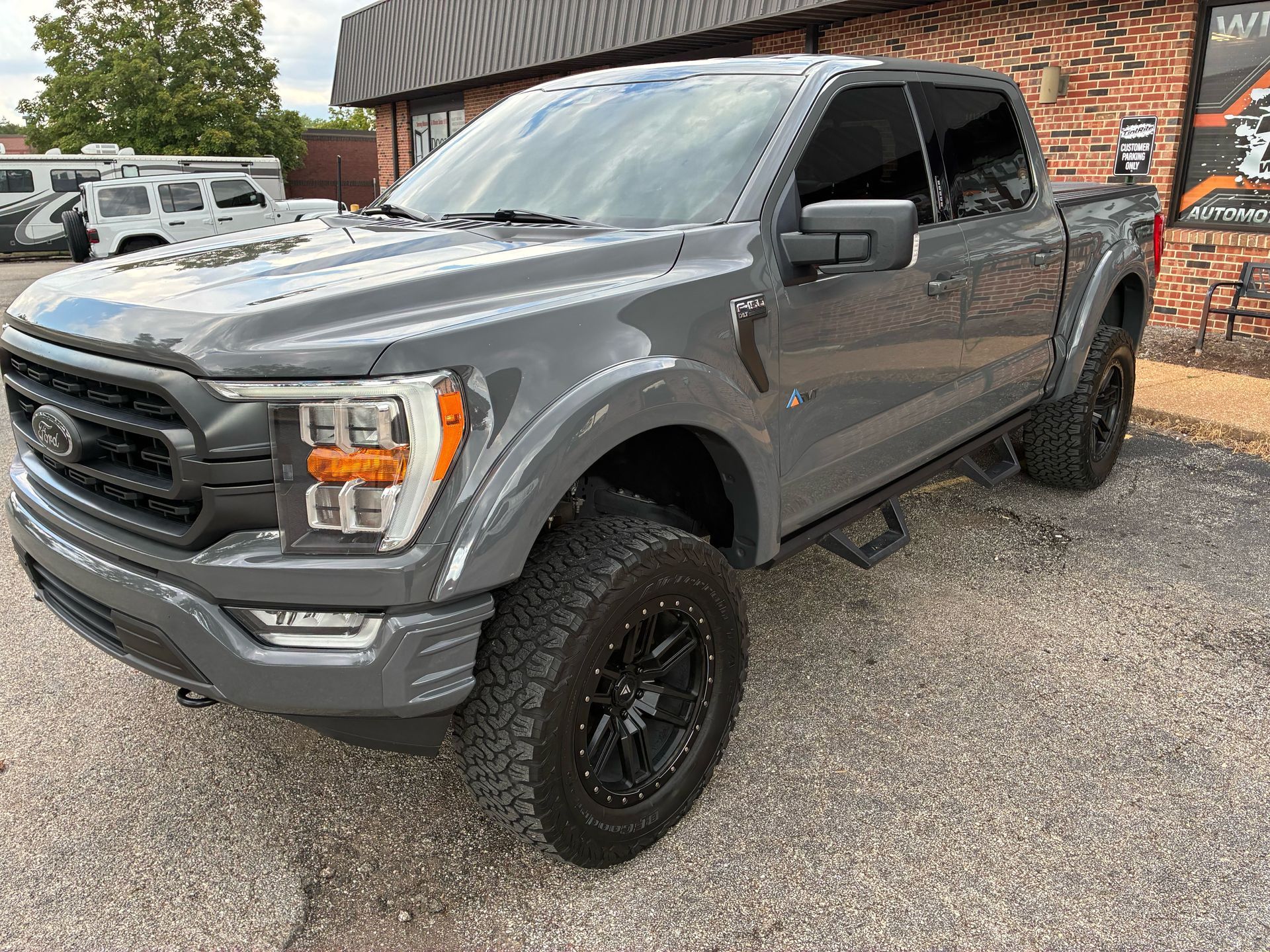 Gray Ford F-150 truck with black wheels parked outside a building.