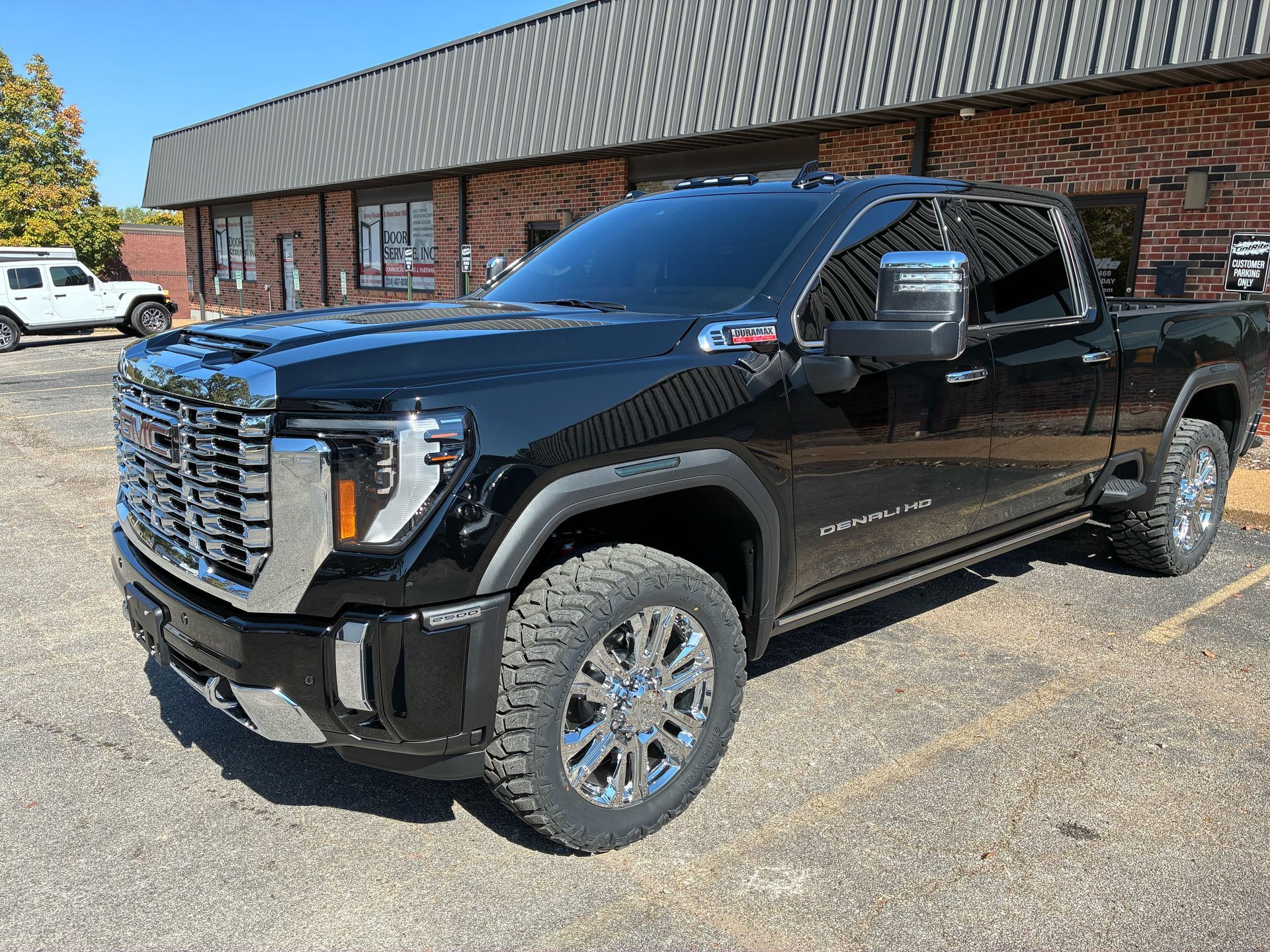 Black GMC Sierra truck parked in front of a building on a sunny day.