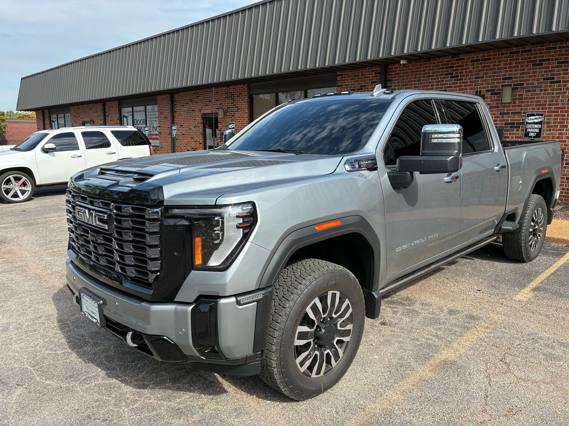 Gray GMC Sierra truck parked outside a building, with a white SUV in the background.