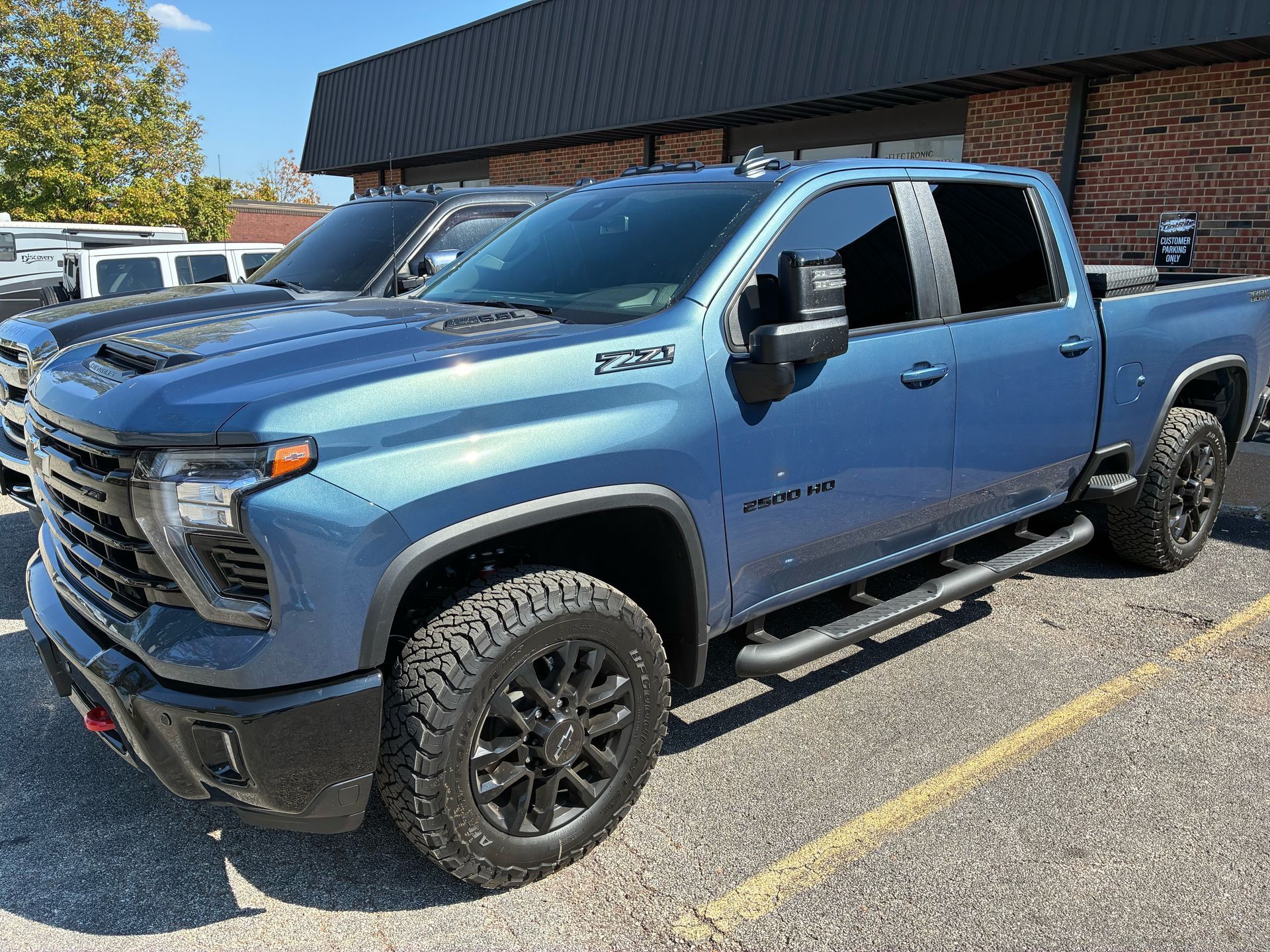 Blue Chevrolet Silverado pickup truck with black wheels parked outside.