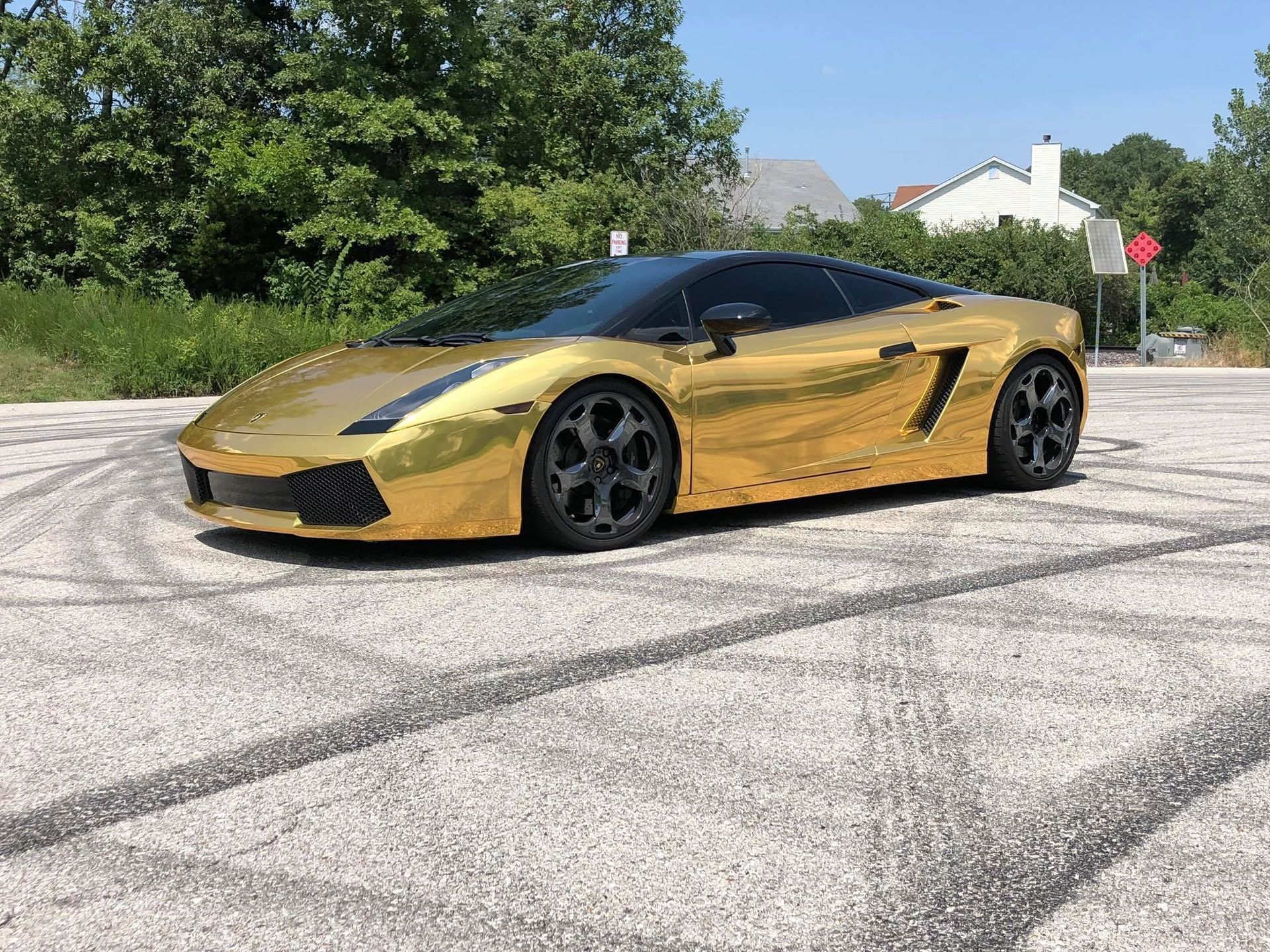 Gold Lamborghini sports car parked on asphalt, black tire marks visible.