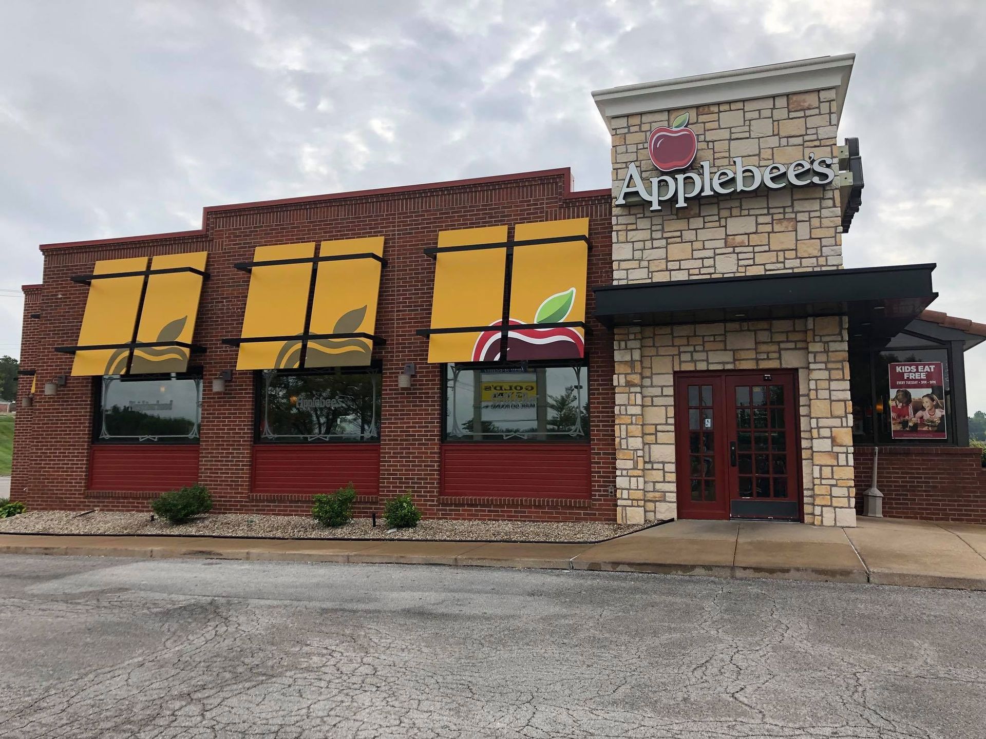 Applebee's restaurant building with a brick exterior, yellow awnings, and a cloudy sky.