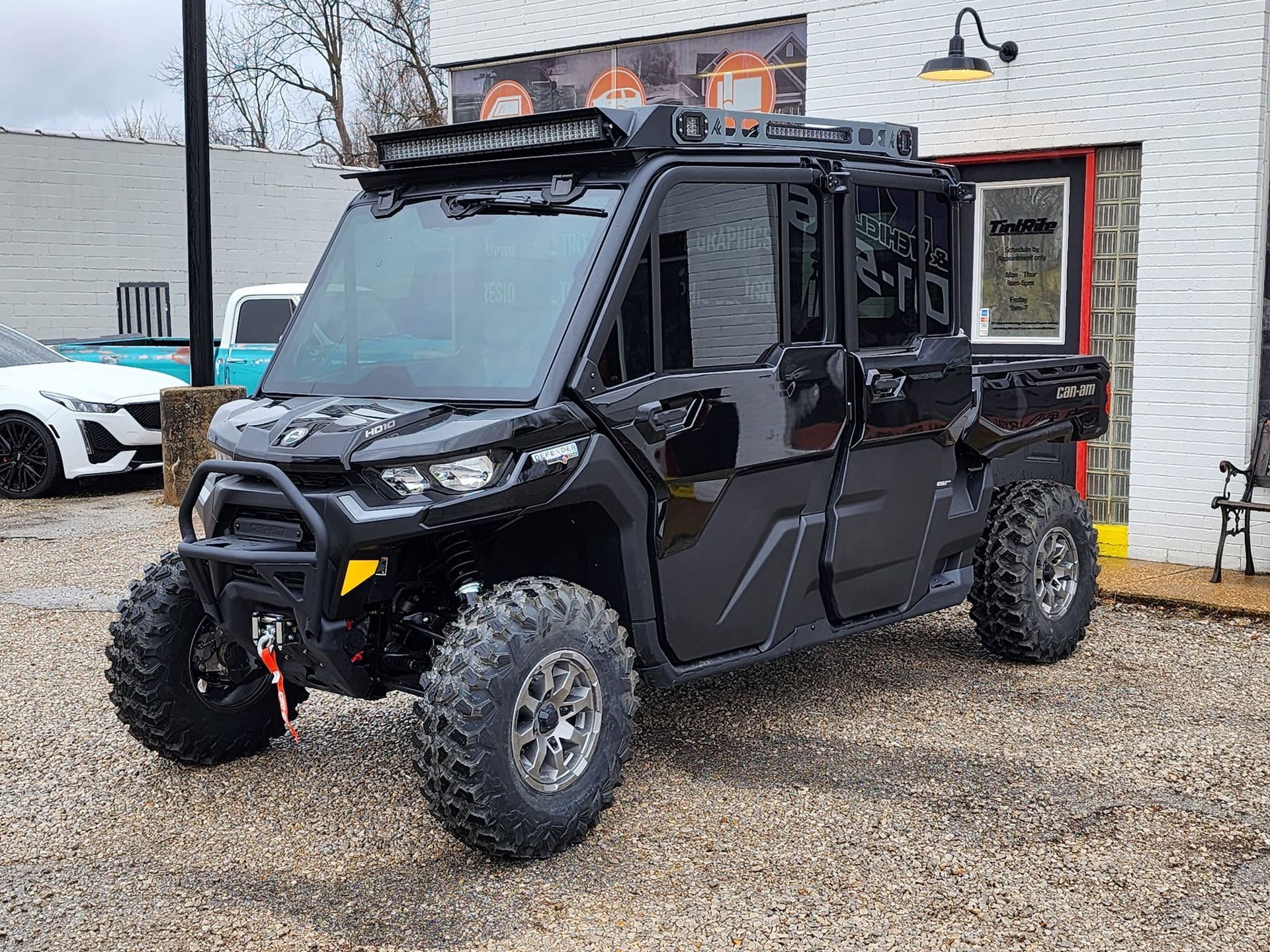 Black off-road vehicle with light bar and rugged tires parked in front of a building.