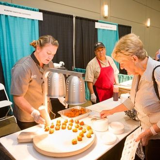 A woman in a chef 's uniform is preparing food on a table