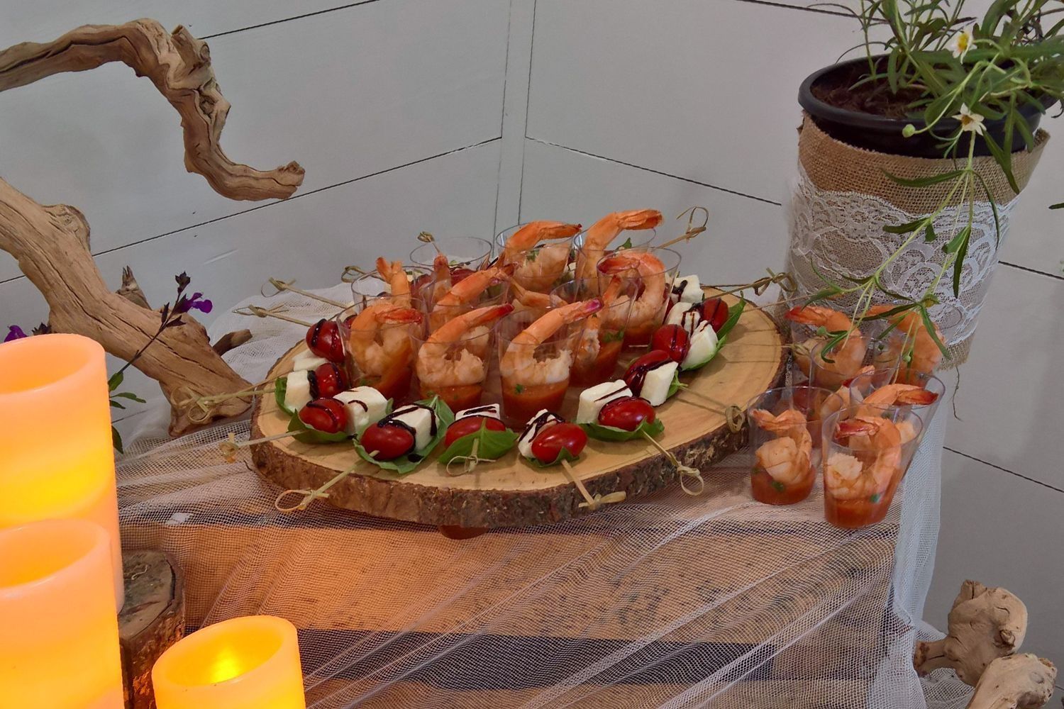 A wooden cutting board topped with shrimp and tomatoes on a table.