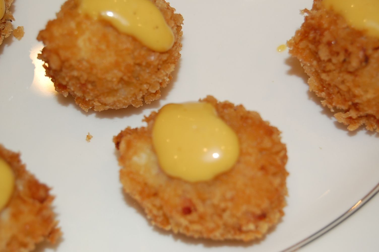 A white plate topped with fried food and yellow sauce