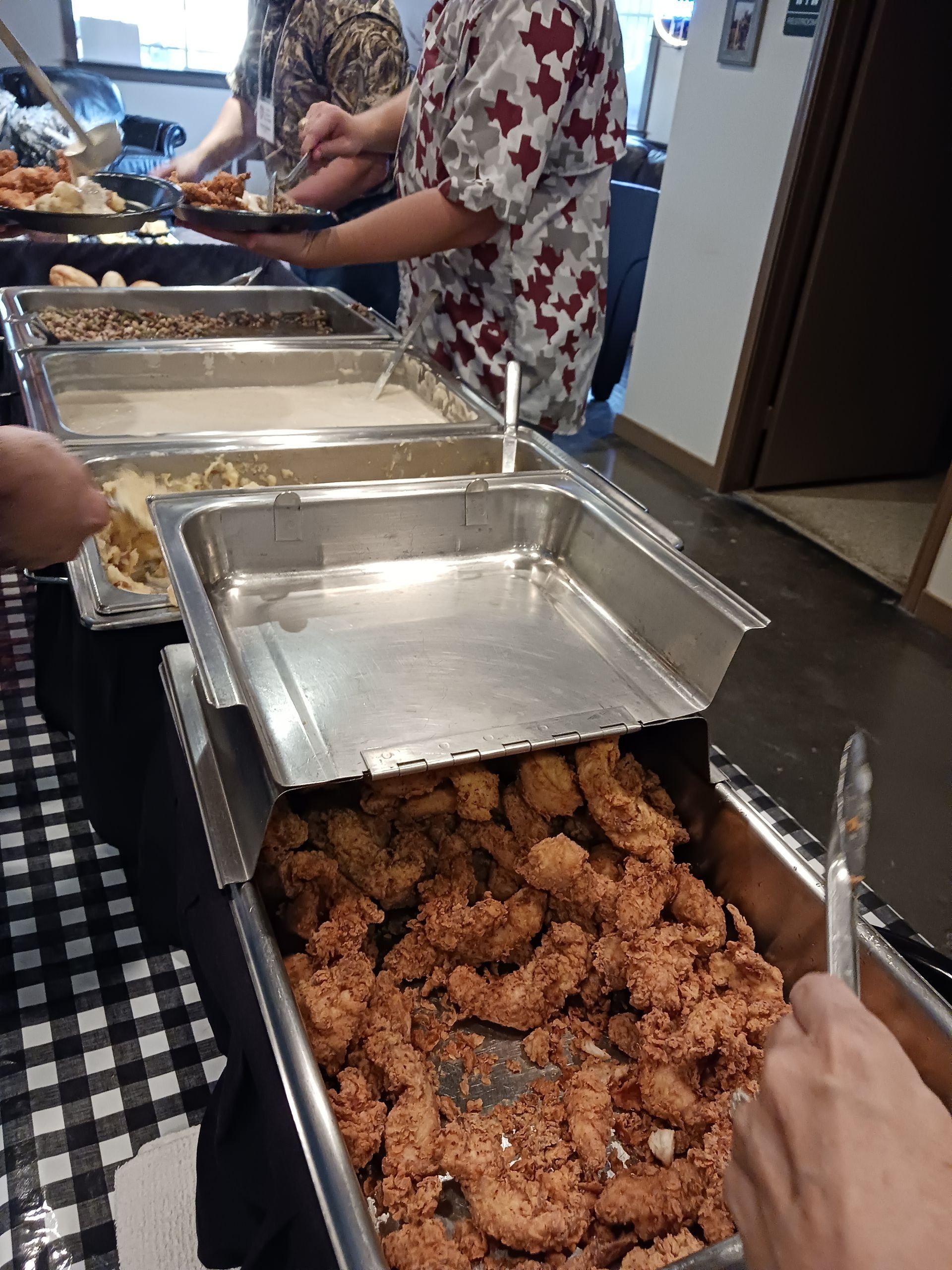A person is holding a fork over a tray of fried chicken.