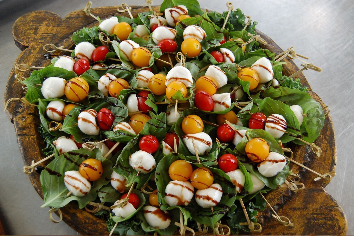 A tray of food with tomatoes and mozzarella on skewers
