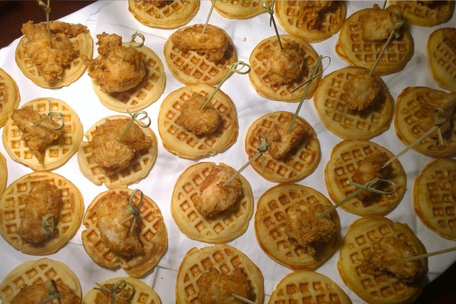 A tray of fried chicken and waffles on toothpicks