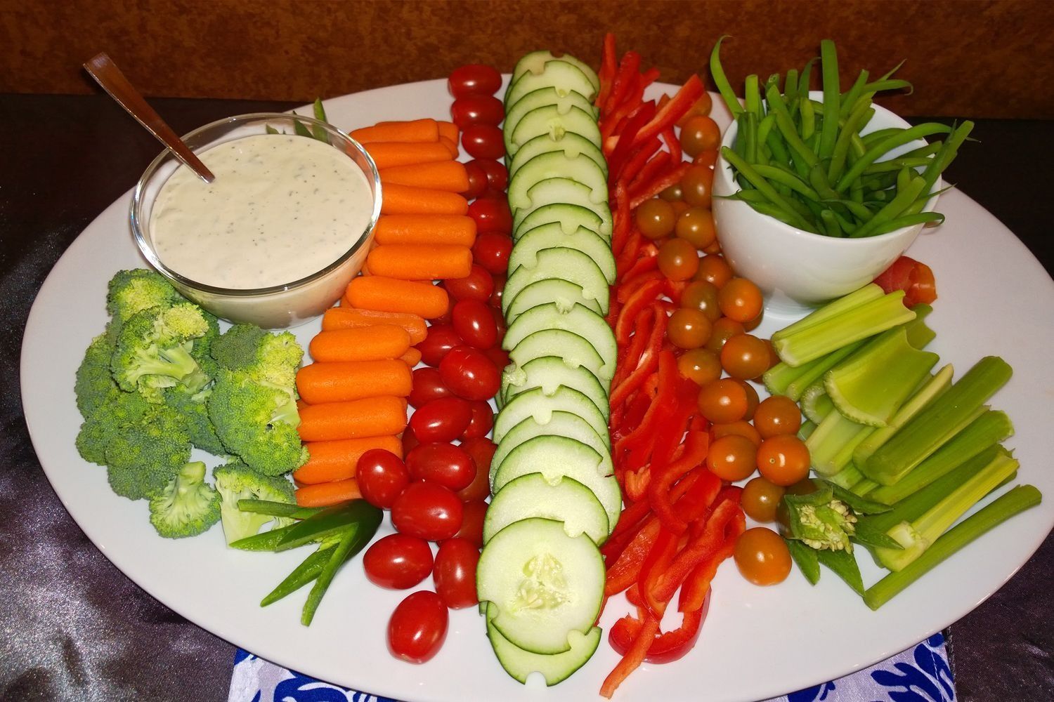 A white plate topped with vegetables and a bowl of dressing
