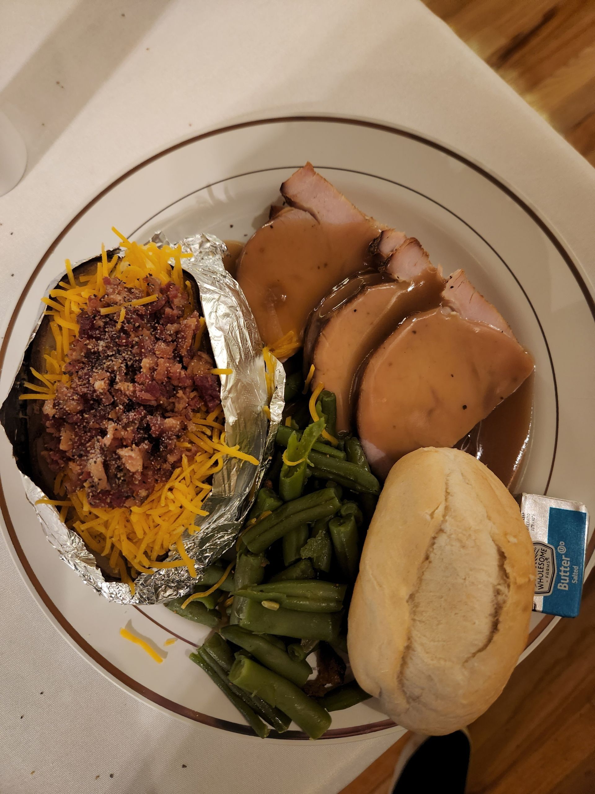 A plate of food with a baked potato and green beans